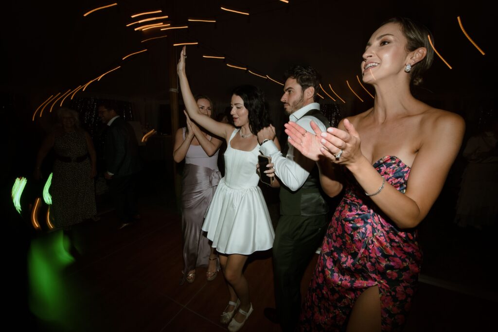 Wedding couple and guests dance at reception in Kohler