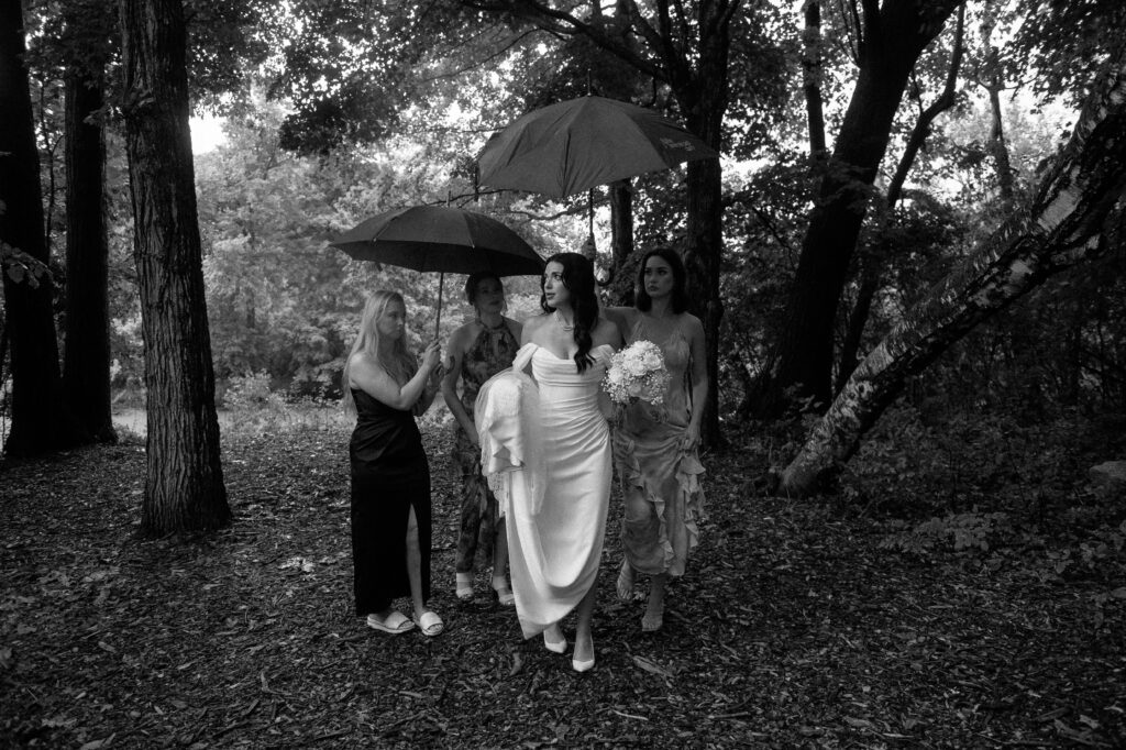 Bride and bridesmaids walking in the rain with umbrellas in Kohler, WI