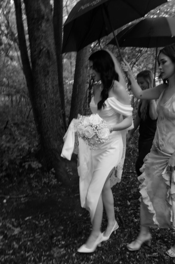 Bride and bridesmaids walk in the rain at River Wildlife