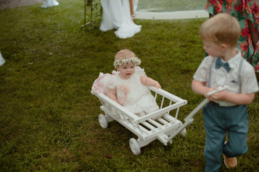 Boy pushing baby girl in a wagon at River Wildlife tent wedding ceremony