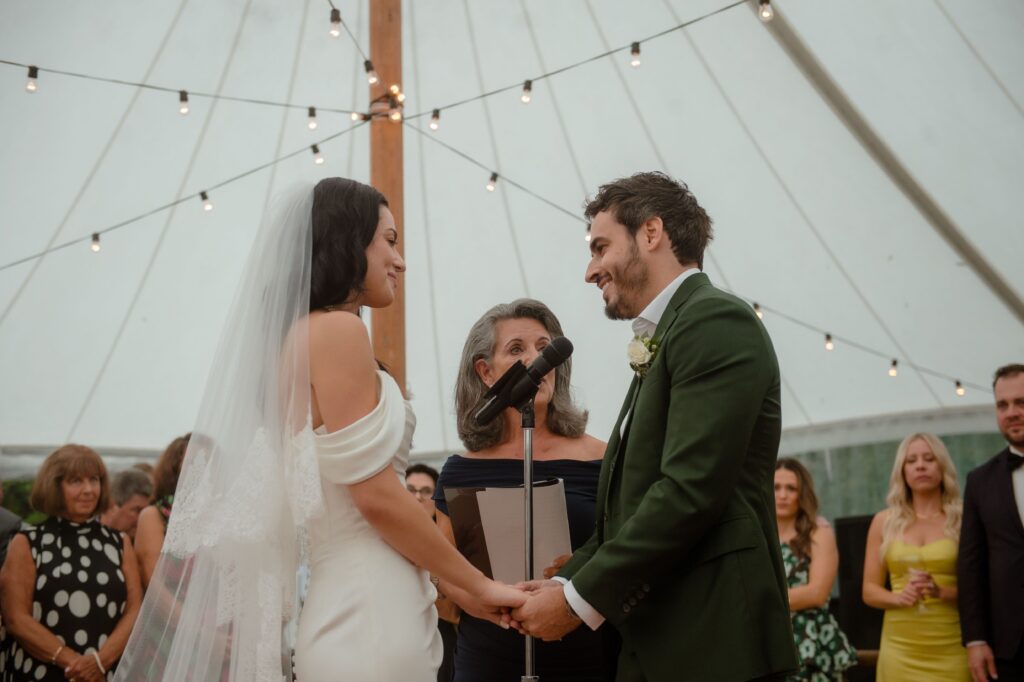 Bride and groom holding hands as they exchange vows at wedding ceremony in Kohler
