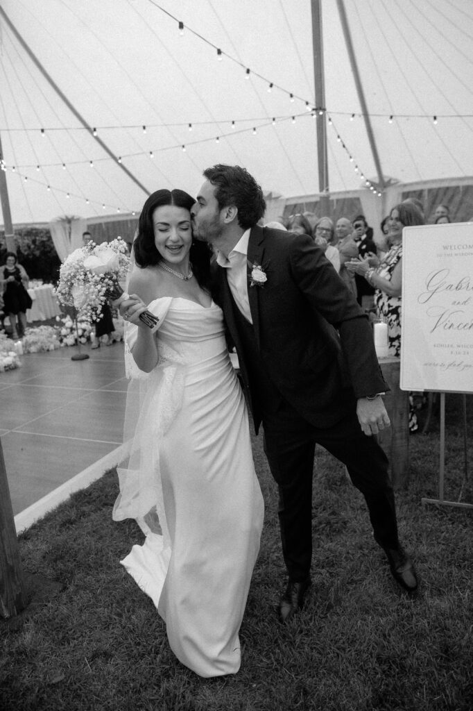Groom kisses bride as they exit their tent wedding ceremony at River Wildlife