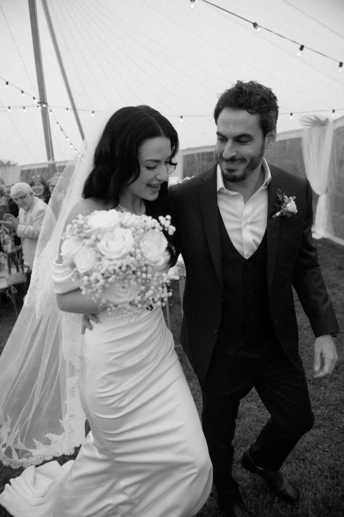 Bride and groom exit their tent wedding reception at American Club