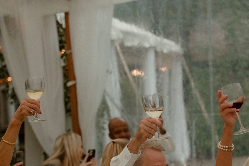 Guests toast during tent wedding reception in Kohler
