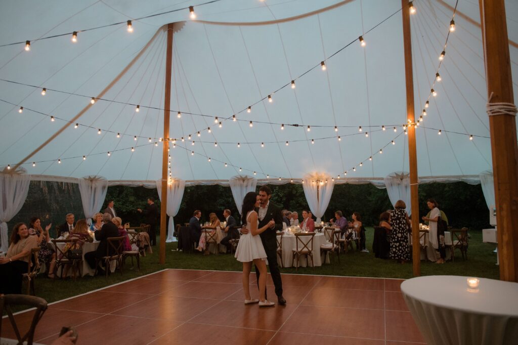 Bride and groom first dance under string lights at tent wedding reception at River Wildlife