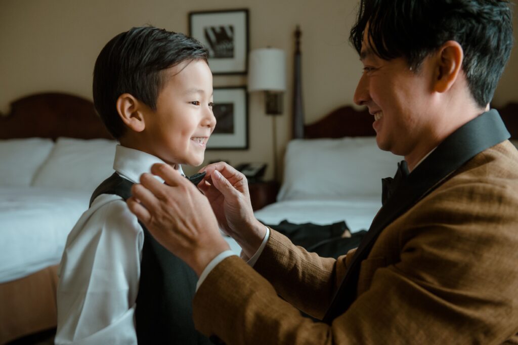 Father ties bow tie for son before wedding at Pfister Hotel in Milwaukee