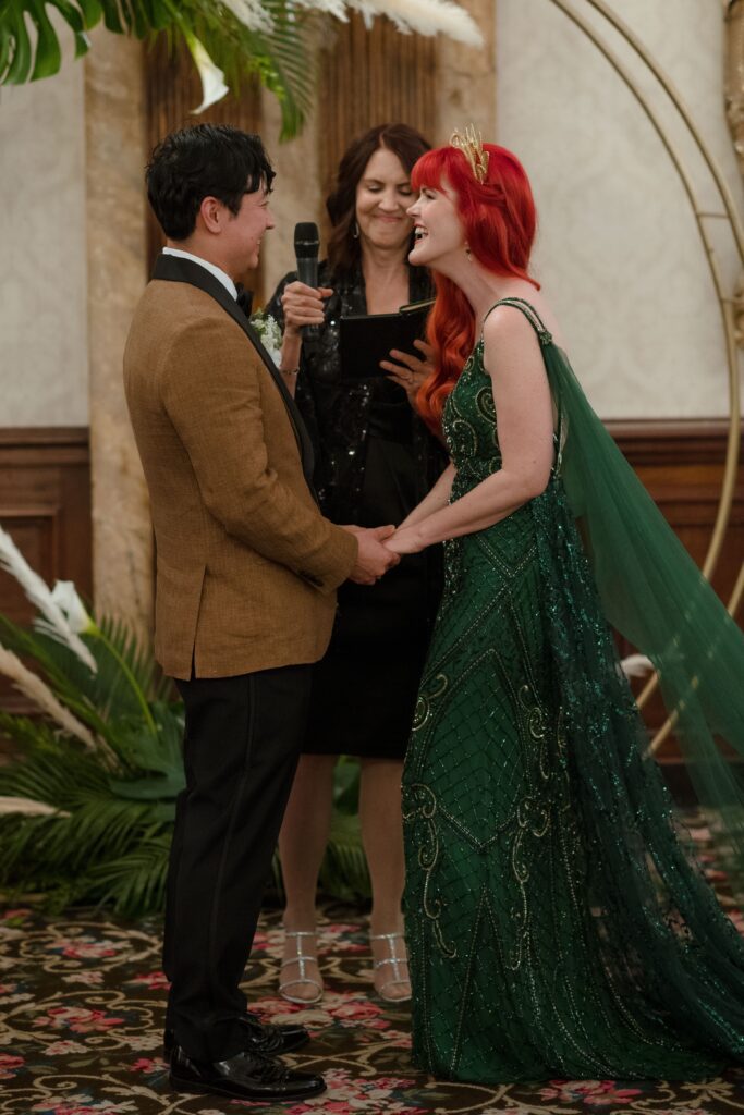 Bride and groom hold hands and laugh together at wedding ceremony in Milwaukee at the Pfister Hotel