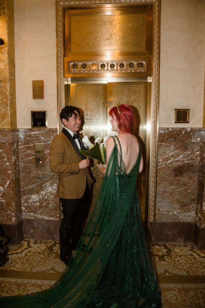 Bride and groom smile at each other by the gold elevator at the Pfister Hotel in Milwaukee