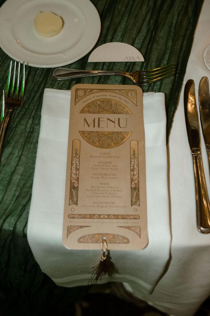 A custom menu sits on a green tablecloth at a wedding reception at the Pfister Hotel in Milwaukee