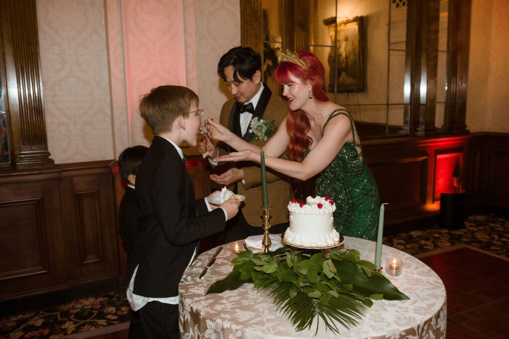 Bride and groom feed cake to their kids during wedding reception at the Pfiser Hotel