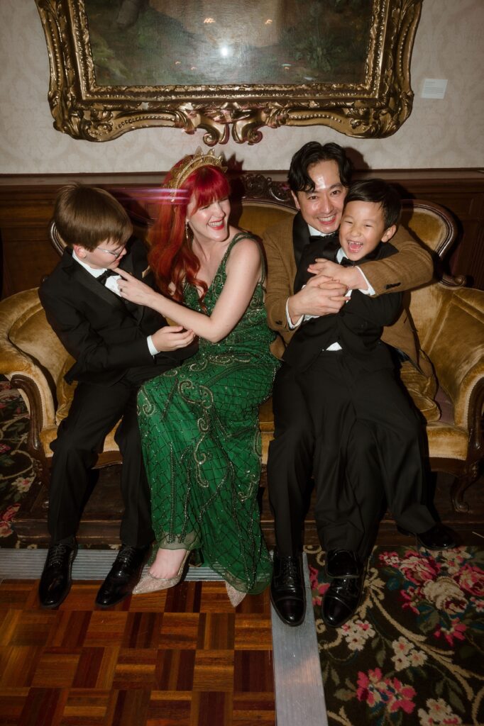 Bride and groom laugh with their kids on a couch at the Pfister Hotel