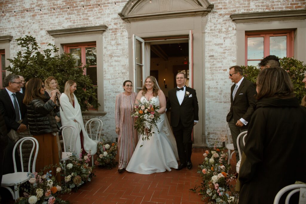Bride walks down the aisle with parents at Villa Terrace