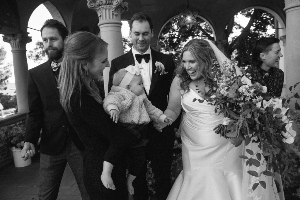 Candid photo of wedding couple and friends laughing in black and white