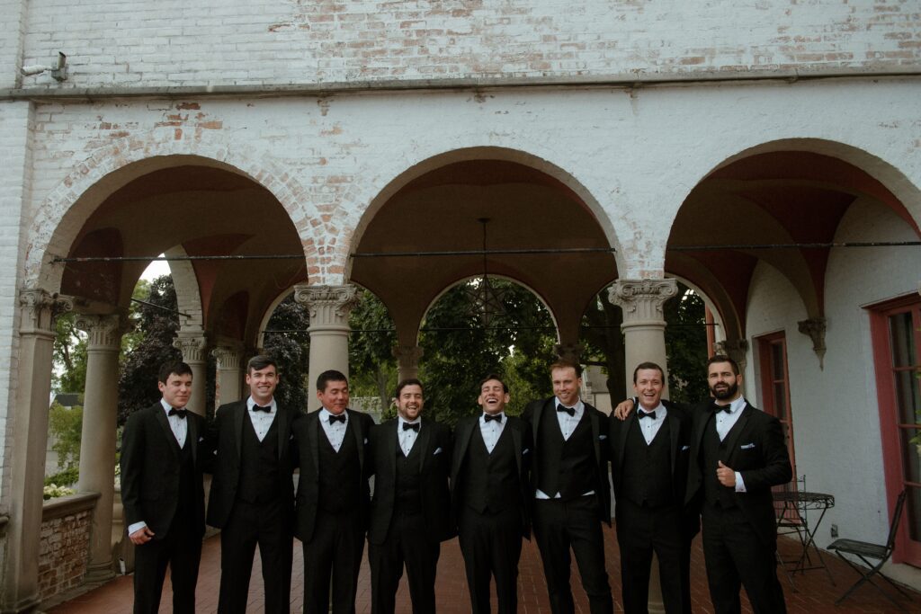 Groomsmen stand in front of Villa Terrace architecture