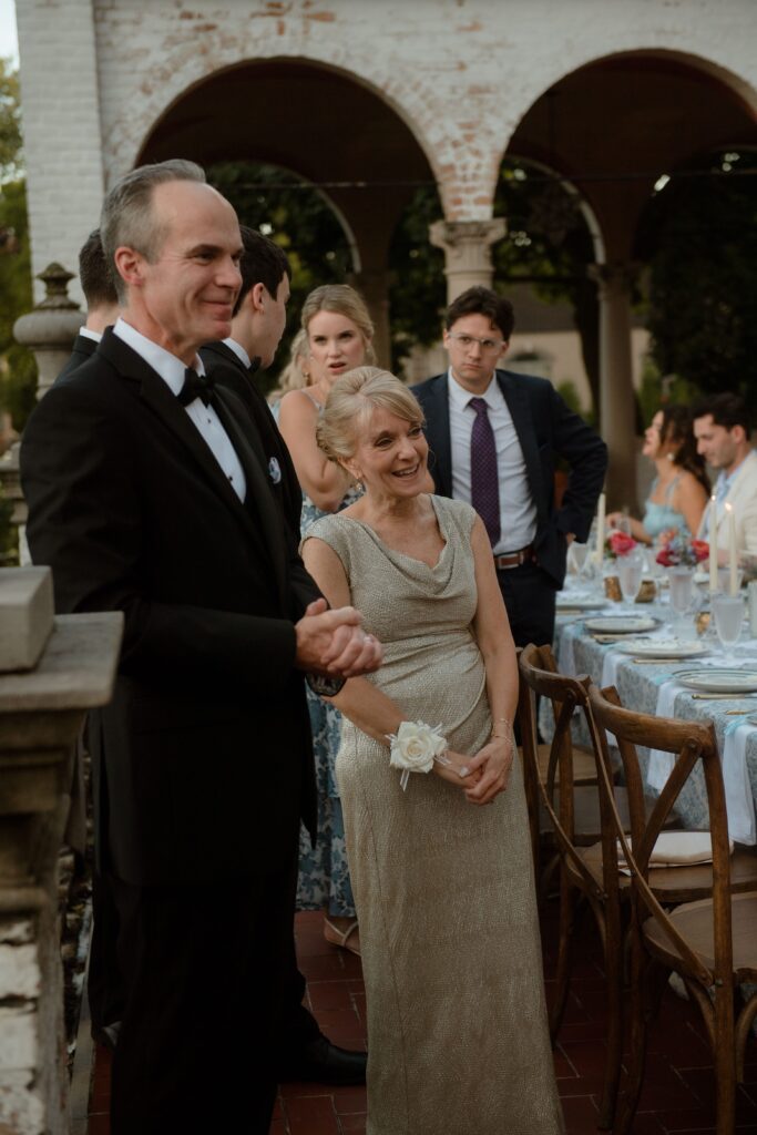 Wedding guests smile on at bride and groom