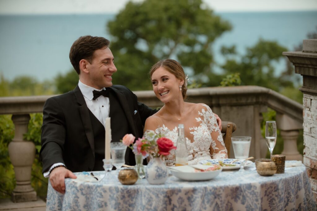 Bride and groom smile at head table at wedding reception at Villa Terrace