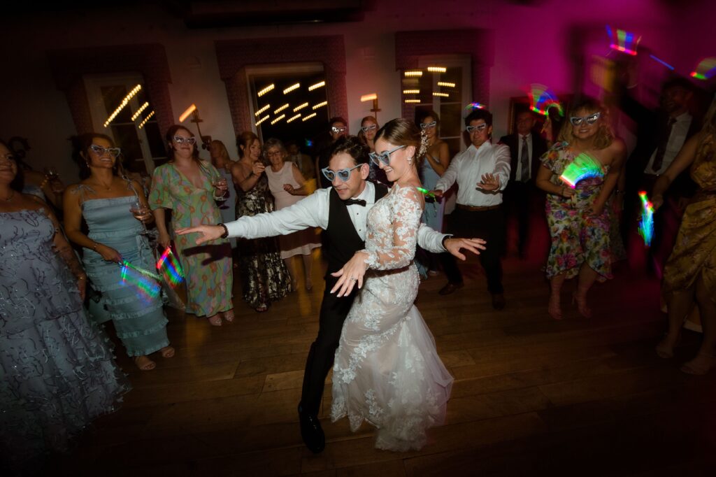 Bride and groom dance with their guests at colorful wedding reception